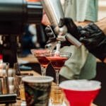 Barmani w barze używają syfonów do bitej śmietany przy koktajlach