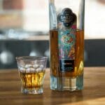 Butelka szkockiej whisky single malt The Lakes i kieliszek na drewnianym stole