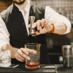Barman odmierza składniki jiggerem i miesza koktajl w eleganckim barze