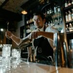Barman precyzyjnie miesza koktajl przy barowym kontuarze