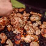 Kawałki grillowanego kurczaka skwierczące na ruszcie nad żarem