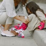 Mama pomaga córce założyć rolki podczas nauki jazdy na dworze