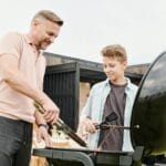 Ojciec i syn przy ogrodowym grillu podczas letniego rodzinnego spotkania