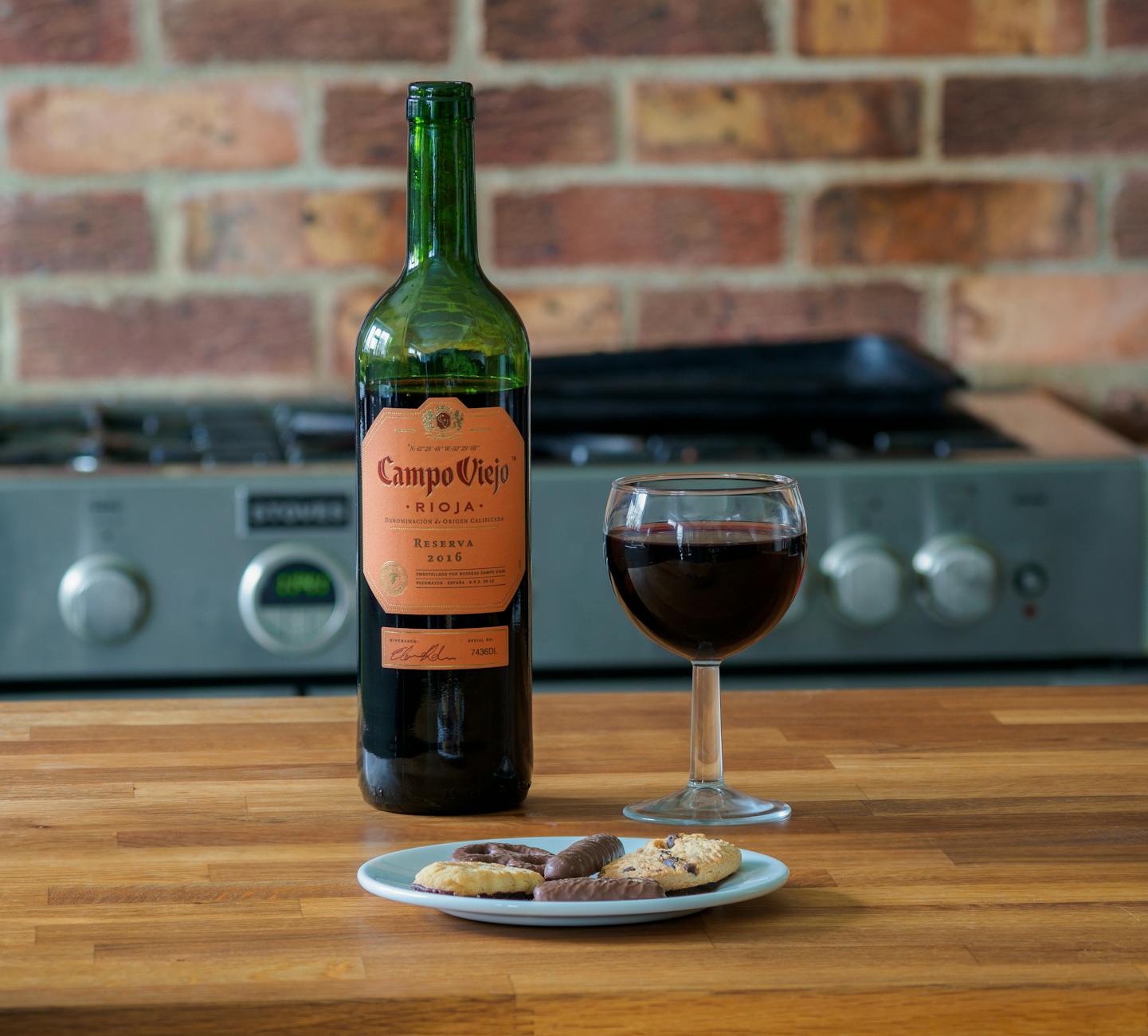 Butelka czerwonego wina i ciasteczka na drewnianym stole w kuchni