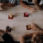 Grupa znajomych pije alkohol przy drewnianym stole z góry