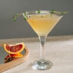 Koktajl grejpfrutowy w kieliszku martini z ziołową dekoracją
