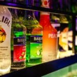 Kolorowe butelki różnych alkoholi ustawione na podświetlonej półce barowej