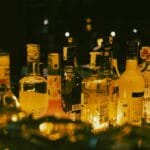 Różne butelki alkoholu na półce w nastrojowym, przyciemnionym barze