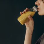 Młoda kobieta pije odżywczy koktajl z butelki po treningu