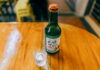 Koreańskie soju: z czym pić ten lekki alkohol i jak serwować go do potraw? Butelka koreańskiego soju i kieliszek na drewnianym stole
