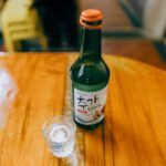 Butelka koreańskiego soju i kieliszek na drewnianym stole