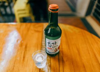 Koreańskie soju: z czym pić ten lekki alkohol i jak serwować go do potraw? Butelka koreańskiego soju i kieliszek na drewnianym stole