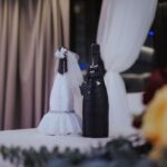 Butelki szampana przebrane za parę młodą na stole weselnym