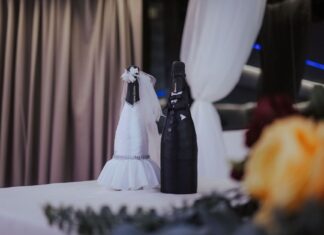 Butelki szampana przebrane za parę młodą na stole weselnym